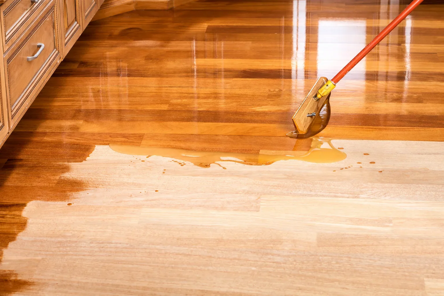 applying finish to hardwood floor with mop