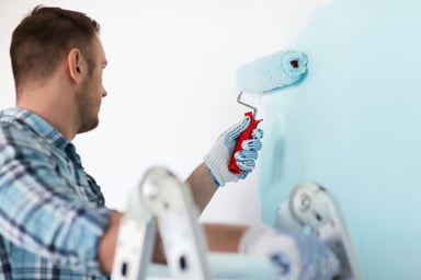 Man painting wall with roller in light blue color